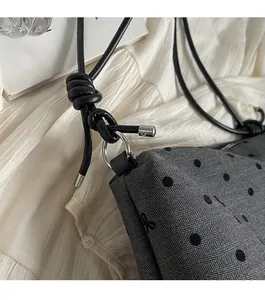 Détail du tissu à chevrons gris avec pois noirs et anneaux en métal argenté