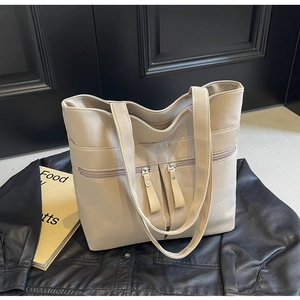 Dettaglio della borsa tote beige in tela con tasche anteriori a cerniera e doppi manici