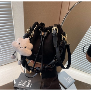 Detail of black suede drawstring bucket bag with woven handle and plush cloud charm