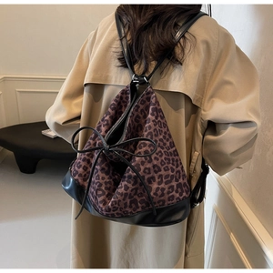 Leopard print canvas backpack with black leather base and large decorative bow detail