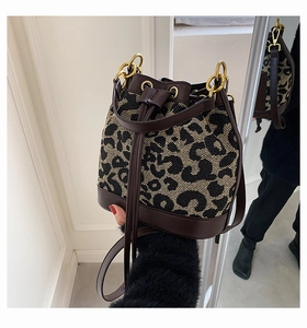 Close-up of leopard print bucket bag with leather drawstring and gold hardware