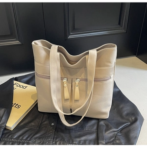 Dettaglio della borsa tote beige in tela con tasche a zip su sfondo di pelle nera