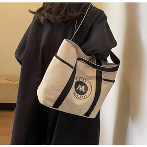Detalle de un bolso tote de lona grande que muestra el logo vintage y los bordes negros