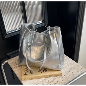 Close-up of silver metallic tote bag with textured finish and triangle logo detail