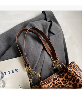 Detail of leopard print handbag with leather handle and gold chain on grey blazer