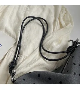 Détail du sac gris à pois avec bandoulière nouée et finitions métalliques argentées