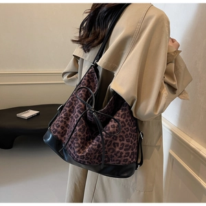 Leopard print bucket bag with black leather trim shown on a model in a trench coat
