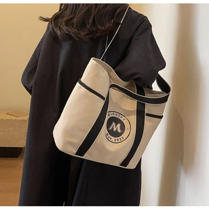 Detalle de un bolso tote grande de lona con ribete negro y logotipo Midolay