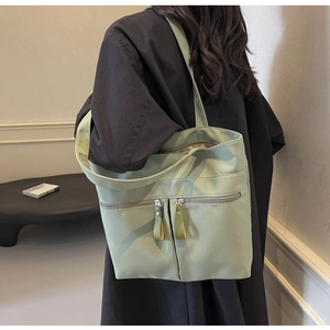 Dettaglio della borsa tote in tela verde chiaro con doppie tasche frontali con cerniera
