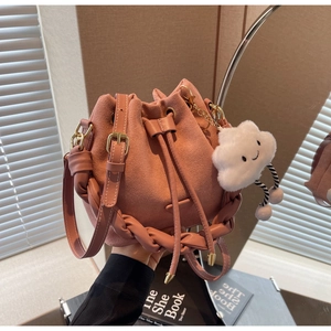 Detail of pink suede bucket bag with woven handle and plush cloud charm accessory