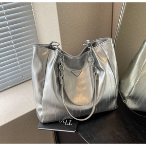 Detail of silver metallic tote bag featuring pleated texture and chain shoulder straps