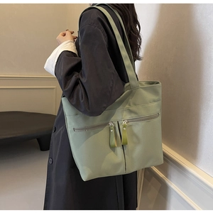Dettaglio della borsa tote in tela verde salvia con doppie cerniere e nappe in pelle