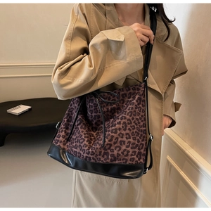 Detail of leopard print bucket bag with black leather bottom shown on a model