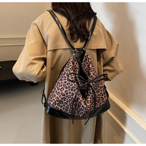 Detailed back view of a leopard print bucket backpack with drawstrings on a model in a coat