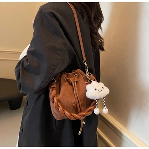 Brown suede bucket bag with braided handle and cute cloud charm shown in lifestyle setting