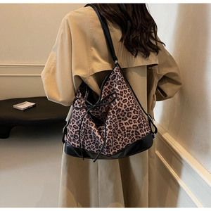 Detail view of a leopard print tote bag with black bow drawstring on a female model