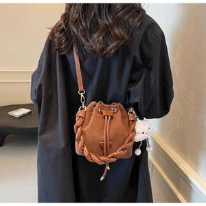 Detailed view of brown suede bucket bag with braided handle and white cloud charm accessory