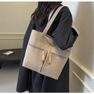 Dettaglio della borsa tote in tela kaki con due tasche frontali con zip e tiranti in pelle