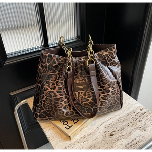 Detail of leopard print tote bag with golden metal chain handle on marble surface