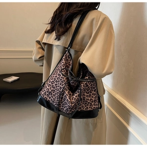 Detail view of leopard print tote bag with black leather straps on a fashion model