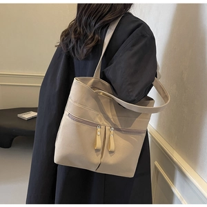 Dettaglio della borsa tote in tela beige con doppie tasche frontali e tiretti in pelle