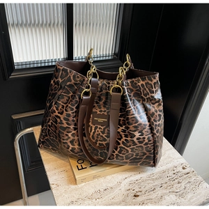 Macro detail of leopard print tote bag with gold chain strap and brown leather handles