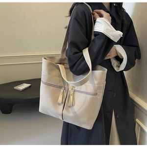 Dettaglio borsa tote in tela beige con doppie tasche con zip e tracolle lunghe per il lavoro