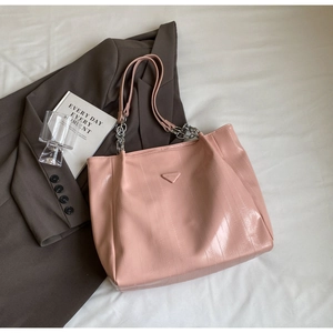 Detail of pink glossy patent leather tote with vertical texture and metal chain strap