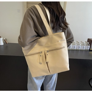 Dettaglio di una grande borsa tote in pelle PU beige con design multitasche con cerniera