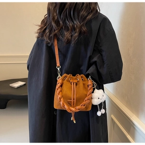 Detail of caramel suede bucket bag with leather woven handle and cute cloud charm pendant