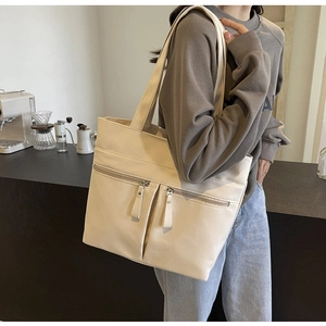 Dettaglio di una borsa tote beige con tre tasche frontali e grande capacità per il lavoro