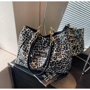Detail of leopard print tote bag with gold chain straps and sleek glossy finish
