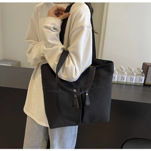 Dettaglio della borsa tote in tela nera con tasca a zip e tasche applicate sul davanti