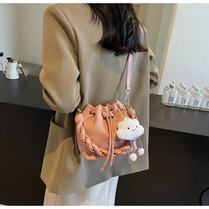 Detail of light pink matte bucket bag with woven strap and cute cloud charm detail