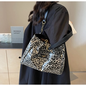 Detail of leopard print tote bag featuring black leather handles and gold metal chains