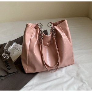 Detail of pink patent leather tote bag with crocodile texture and silver chain strap
