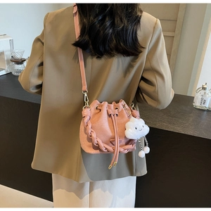 Pink matte bucket bag with woven handle and plush cloud charm shown on shoulder