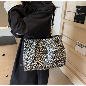 Detail of leopard print tote bag with metal chain strap and brand leather tag