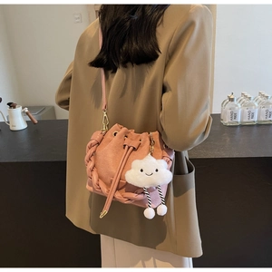 Detail of pink suede bucket bag with woven handle and plush cloud charm accessory