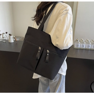 Dettaglio della borsa tote in tela nera con doppie tasche frontali con cerniera per ufficio