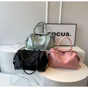 Trois grands sacs de voyage en nylon en menthe, rose et noir sur un support minimal