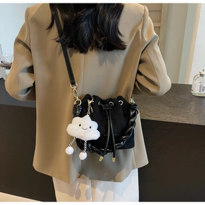 Detail of black suede bucket bag with woven handle and cute cloud plush charm
