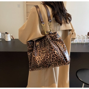 Detail view of leopard print tote bag with gold chain strap and square metal logo