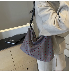 Sac cabas en toile grise à motifs cœurs rouges avec bandoulière à nœud porté par mannequin