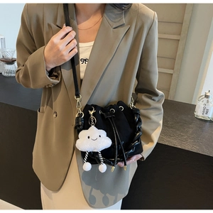 Detail of black drawstring bucket bag with cute plush cloud charm and gold hardware