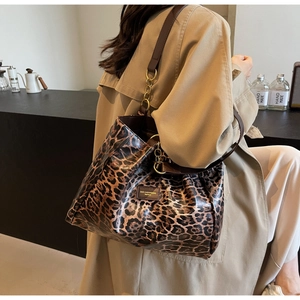 Detail of leopard print tote bag with brown straps and golden chain decoration