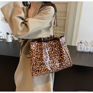 Detail of leopard print tote bag with brown leather straps and golden chain decoration