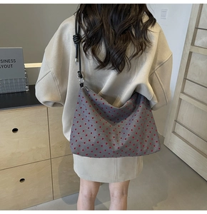 Vue arrière du modèle portant un grand sac cabas en nylon gris avec motifs de cœurs