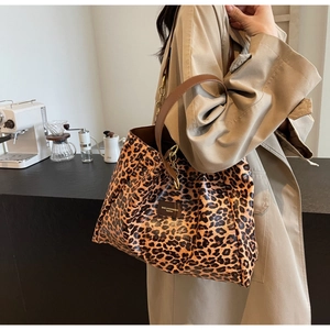 Detailed view of large leopard print tote bag with brown handles and chain on a model