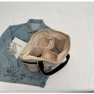 Detalle del interior de un bolso grande de lona con bolsillo de cremallera y compartimento